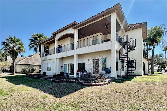 back of house featuring stairs, a lawn, a ceiling fan, and stucco siding