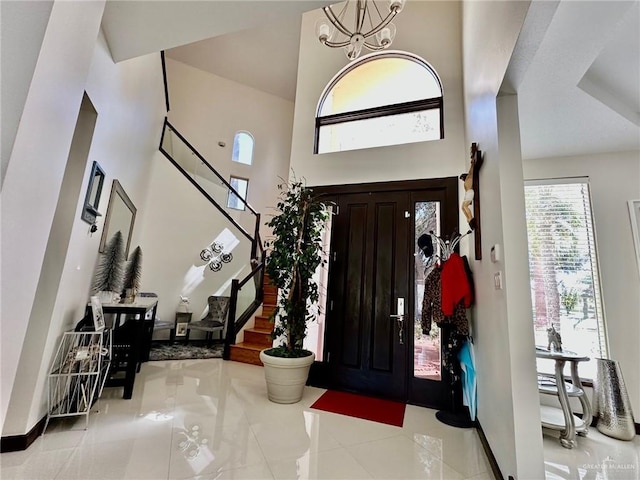 entrance foyer with a chandelier, light tile patterned floors, a towering ceiling, baseboards, and stairway