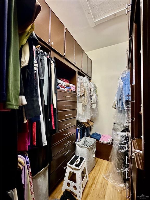 walk in closet with light wood-style flooring