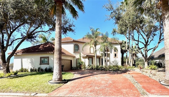 mediterranean / spanish-style home with a front lawn, decorative driveway, and stucco siding