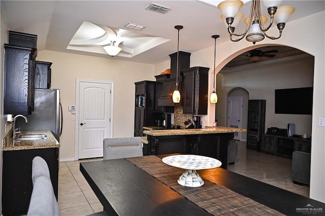 tiled dining area with ceiling fan with notable chandelier, a tray ceiling, and sink