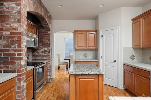 kitchen featuring stainless steel appliances, a center island, backsplash, and light hardwood / wood-style flooring