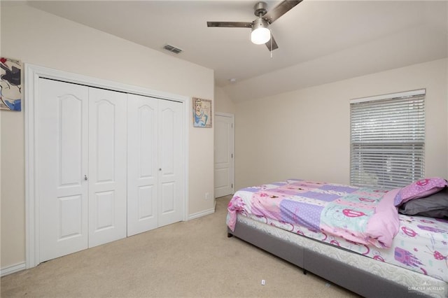 bedroom with vaulted ceiling, light colored carpet, a closet, and ceiling fan