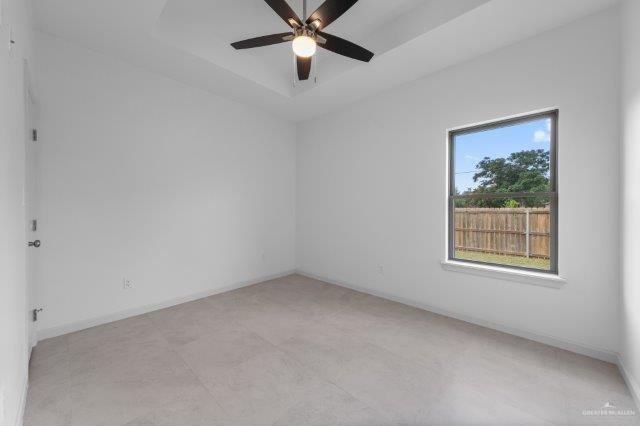 1212 Bridle Way, San Benito, TX 78586 - empty room featuring ceiling fan, a raised ceiling, and baseboards