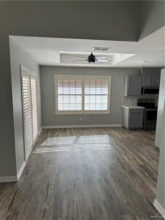 interior space with dark wood-type flooring, baseboards, visible vents, and ceiling fan