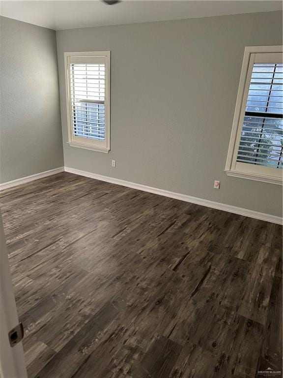 spare room with baseboards and dark wood finished floors