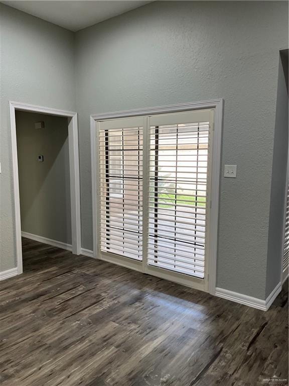 spare room featuring baseboards, wood finished floors, and a textured wall