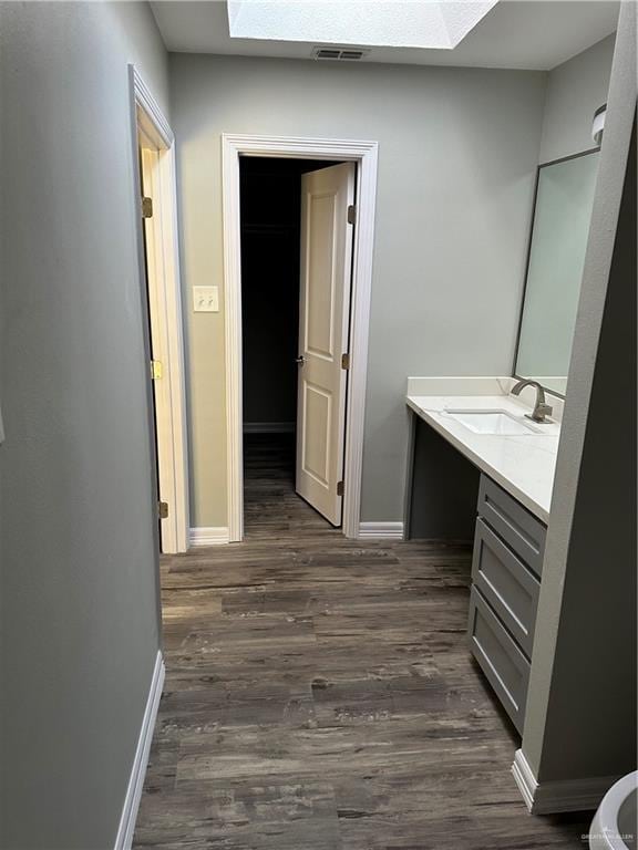 bathroom featuring visible vents, wood finished floors, a skylight, baseboards, and vanity