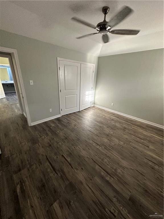 unfurnished bedroom with a ceiling fan, baseboards, dark wood-type flooring, a closet, and a textured ceiling