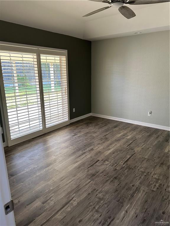 unfurnished room featuring a ceiling fan, dark wood-style floors, and baseboards