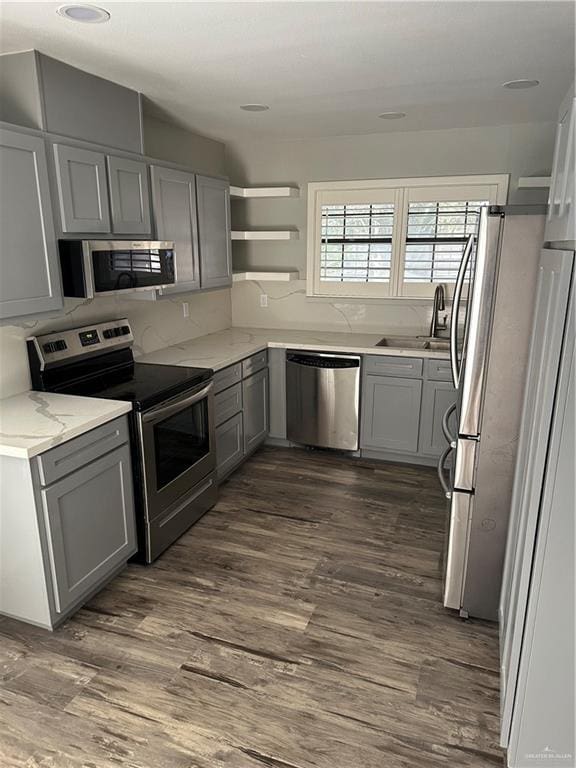 kitchen featuring a sink, appliances with stainless steel finishes, dark wood finished floors, and gray cabinets