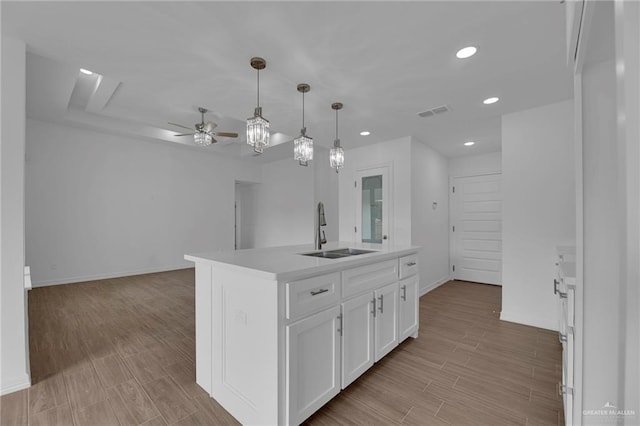 kitchen featuring a center island with sink, white cabinets, sink, light hardwood / wood-style flooring, and ceiling fan