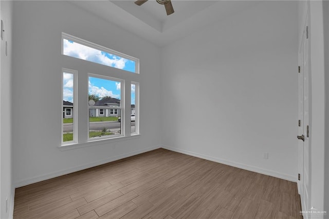 spare room featuring ceiling fan, a towering ceiling, and light wood-type flooring