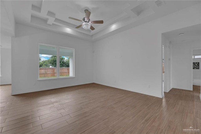 spare room featuring a raised ceiling, light hardwood / wood-style flooring, ceiling fan, and coffered ceiling