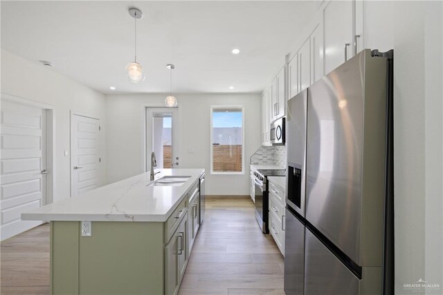 1218 N Lincoln Ave, San Juan, TX 78589 - kitchen with appliances with stainless steel finishes, a sink, light wood finished floors, a center island with sink, and white cabinetry