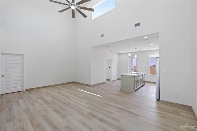 1218 N Lincoln Ave, San Juan, TX 78589 - unfurnished living room with ceiling fan, healthy amount of natural light, light wood finished floors, and a towering ceiling