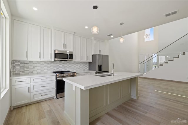 1218 N Lincoln Ave, San Juan, TX 78589 - kitchen with appliances with stainless steel finishes, a sink, light wood-style flooring, backsplash, and an island with sink