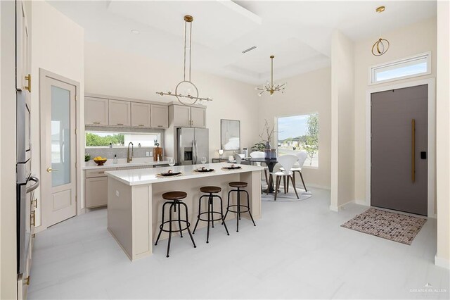 kitchen with stainless steel refrigerator with ice dispenser, light countertops, a breakfast bar, and plenty of natural light
