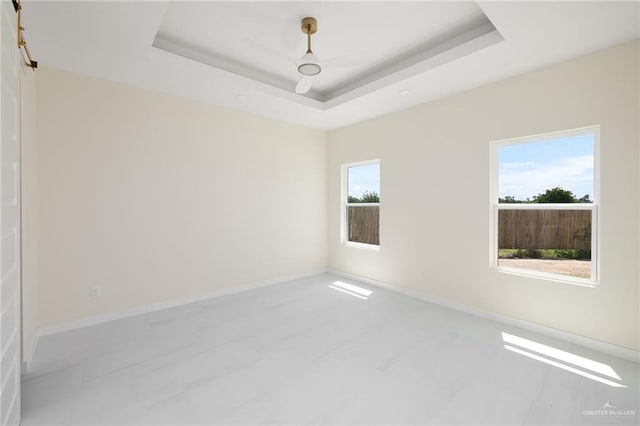 spare room with a tray ceiling and baseboards