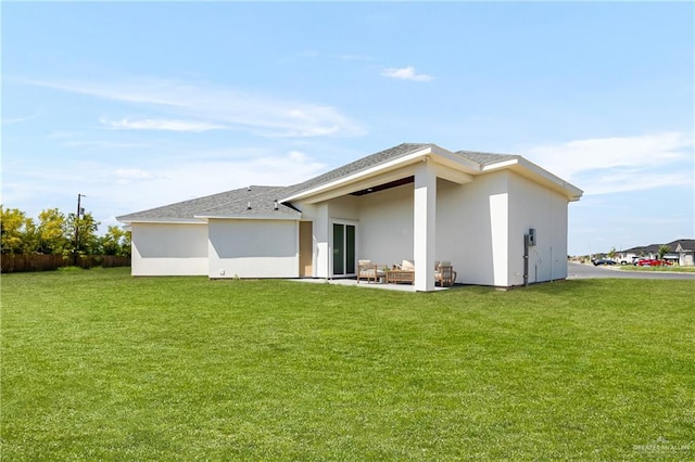rear view of house featuring stucco siding, roof with shingles, a patio area, and a yard