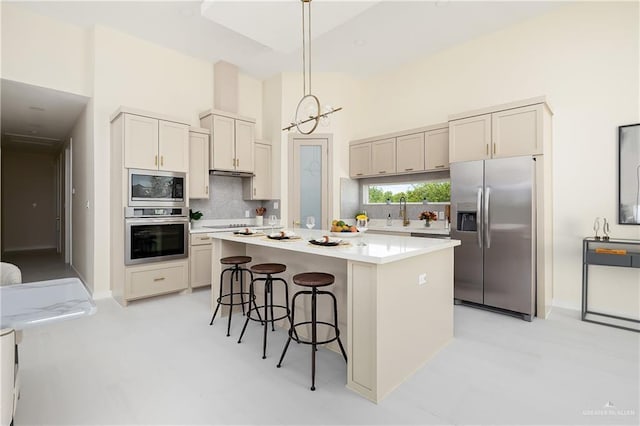 kitchen with stainless steel appliances, tasteful backsplash, a kitchen bar, a high ceiling, and light countertops