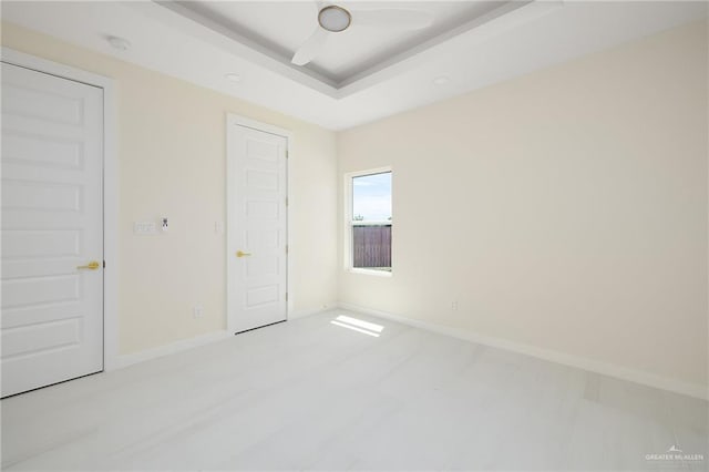 unfurnished bedroom with baseboards and a tray ceiling