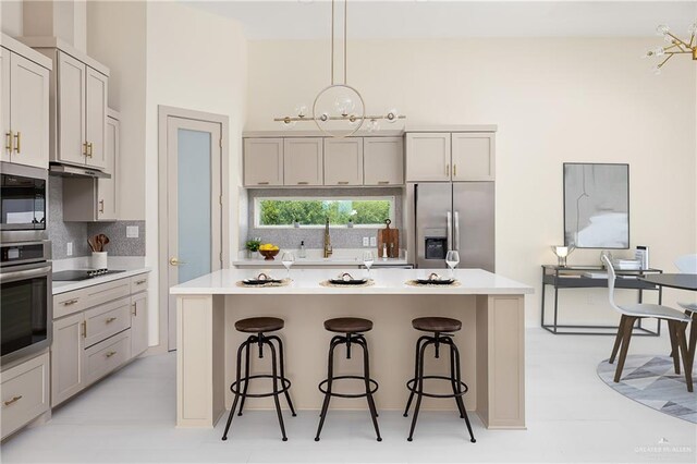 kitchen with stainless steel appliances, backsplash, a sink, a kitchen island, and a breakfast bar area
