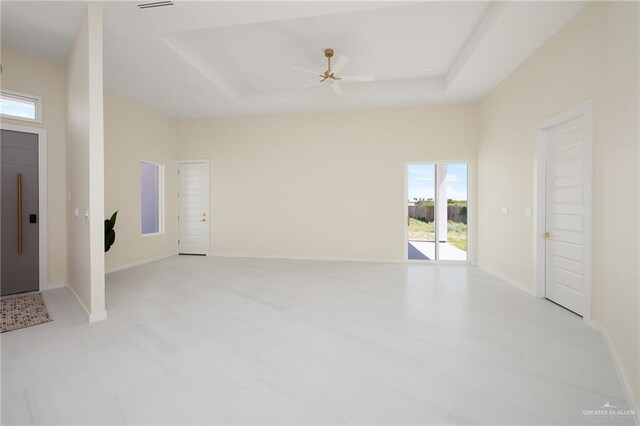 interior space featuring a raised ceiling, plenty of natural light, and baseboards