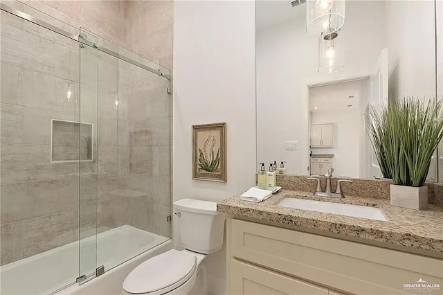 full bathroom featuring toilet, vanity, and shower / bath combination with glass door