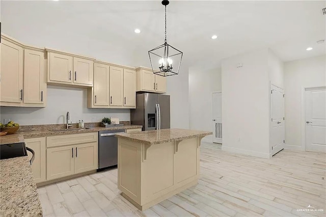 kitchen featuring hanging light fixtures, a center island, stainless steel appliances, and cream cabinets