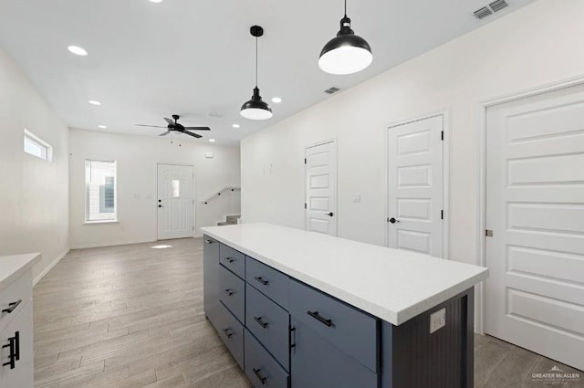 kitchen with light hardwood / wood-style flooring, hanging light fixtures, a kitchen island, and ceiling fan