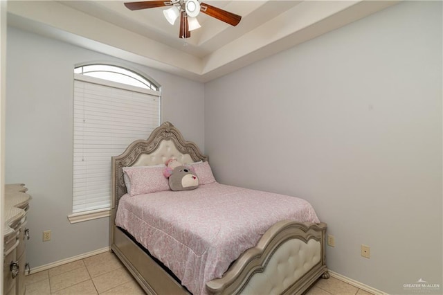 bedroom with light tile patterned floors, a tray ceiling, a ceiling fan, and baseboards