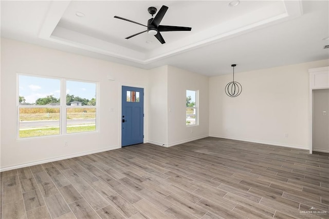 spare room featuring a raised ceiling, ceiling fan, and light wood-type flooring