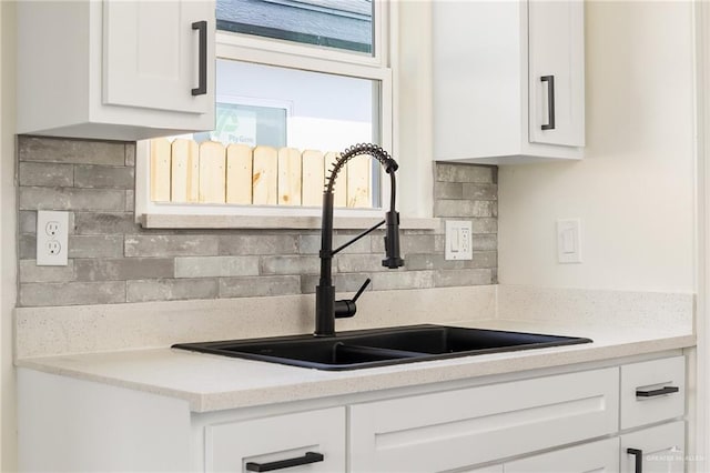 kitchen with decorative backsplash, white cabinetry, and sink