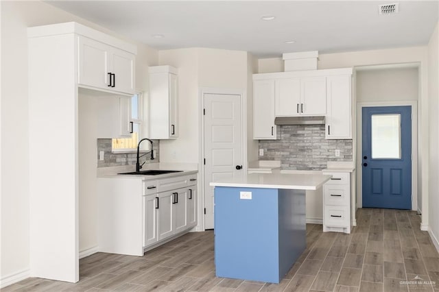 kitchen featuring white cabinetry, a center island, light wood-type flooring, and sink