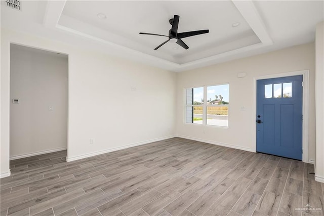 foyer featuring ceiling fan, a raised ceiling, and light wood-type flooring