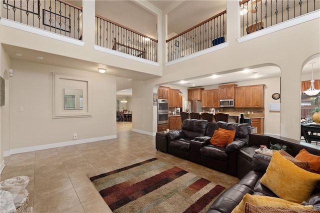 4230 Stillwater Cv, Edinburg, TX 78542 - living area featuring light tile patterned floors, arched walkways, a towering ceiling, and baseboards
