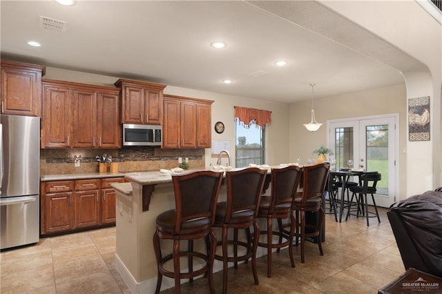 4230 Stillwater Cv, Edinburg, TX 78542 - kitchen with decorative backsplash, a kitchen breakfast bar, visible vents, and appliances with stainless steel finishes