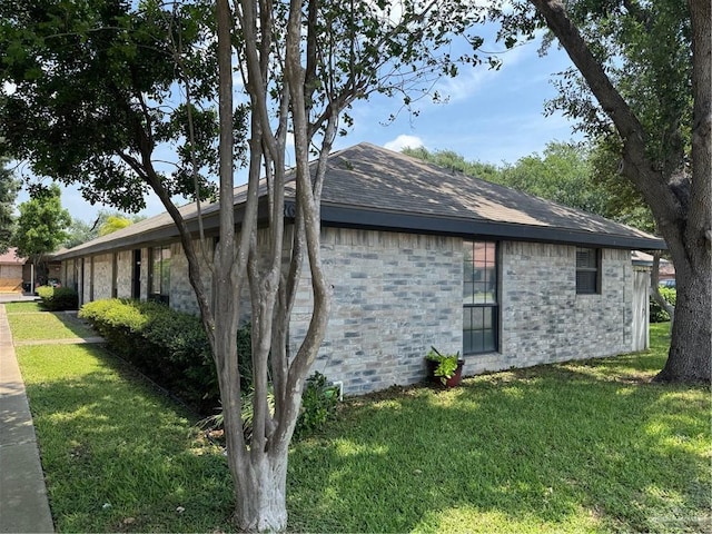 view of home's exterior featuring a shingled roof, a yard, and stone siding