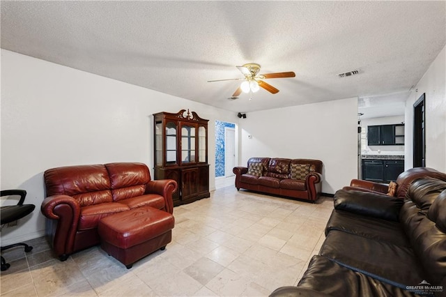 living room with ceiling fan and a textured ceiling