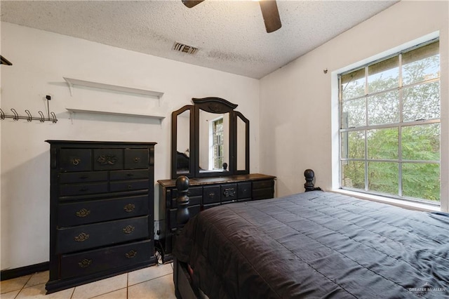 bedroom featuring ceiling fan, a textured ceiling, and light tile patterned floors