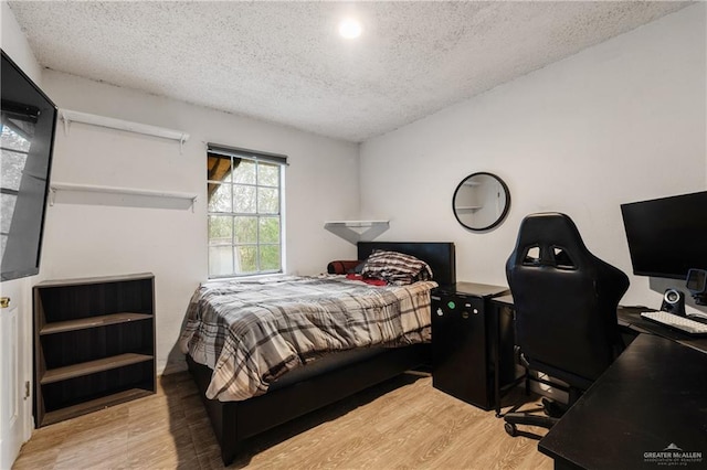 bedroom with a textured ceiling and light wood-type flooring