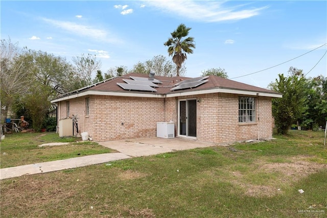 rear view of property featuring a yard, a patio, and solar panels