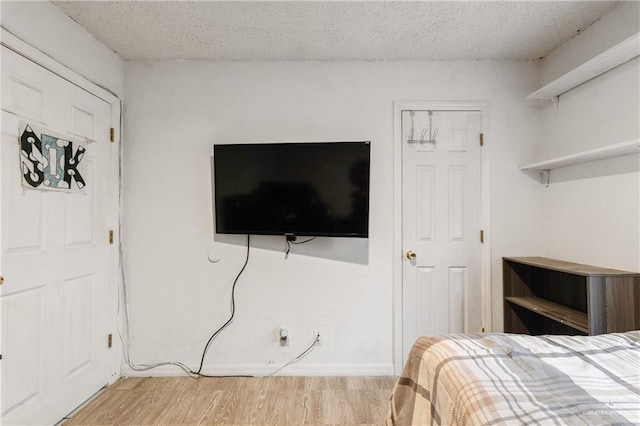 bedroom featuring a textured ceiling and light hardwood / wood-style flooring