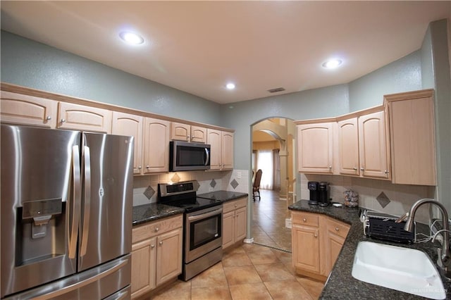 3109 Viola Dr, Mission, TX 78574 - kitchen featuring stainless steel appliances, a sink, arched walkways, light brown cabinets, and tasteful backsplash