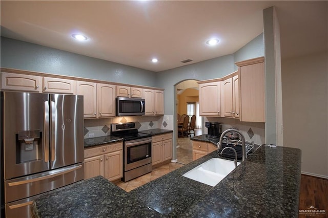 3109 Viola Dr, Mission, TX 78574 - kitchen featuring appliances with stainless steel finishes, a sink, arched walkways, tasteful backsplash, and light brown cabinets
