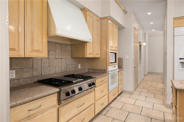 kitchen with premium range hood, backsplash, light brown cabinets, and white appliances