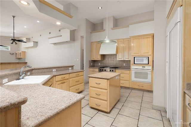 kitchen featuring light brown cabinetry, white appliances, decorative light fixtures, and a kitchen island