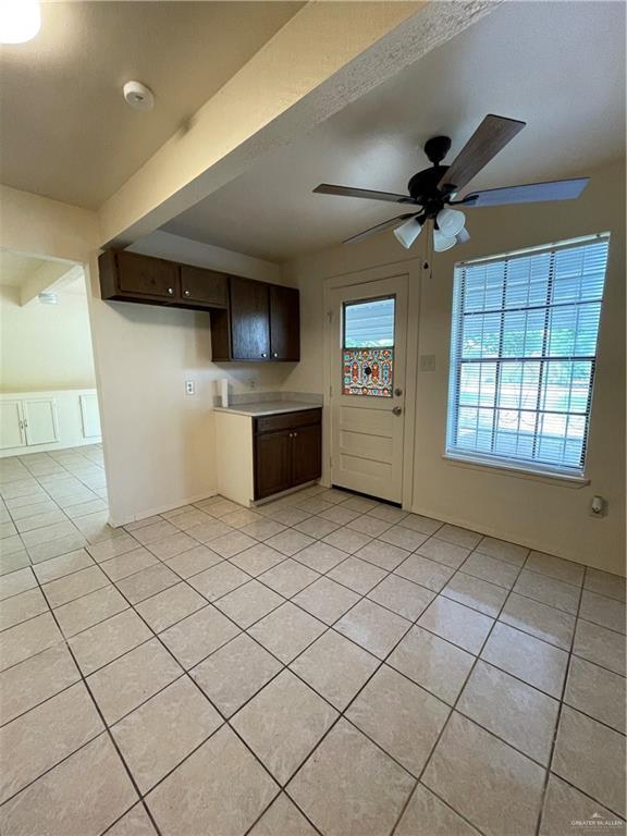 kitchen with beam ceiling, dark brown cabinetry, ceiling fan, and light tile patterned floors