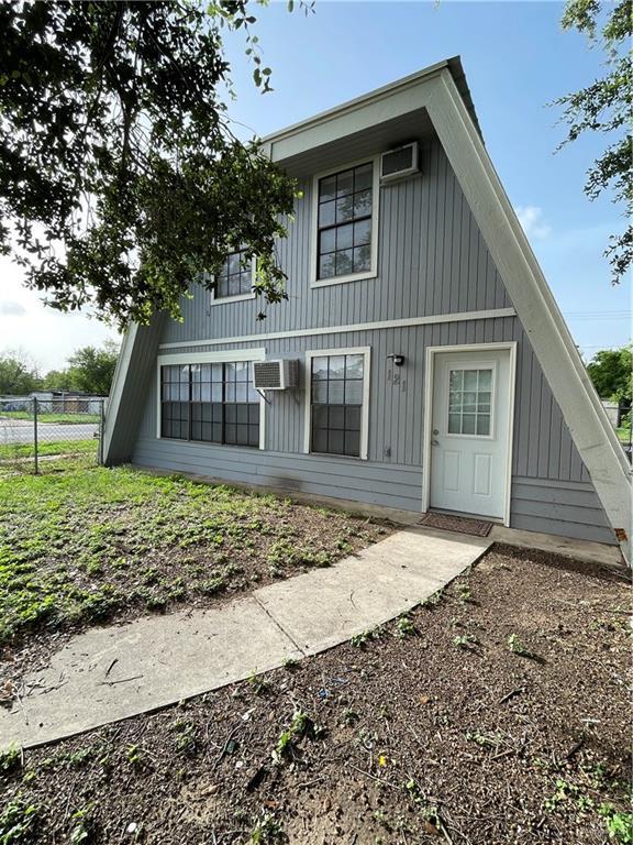 back of property featuring a wall unit AC